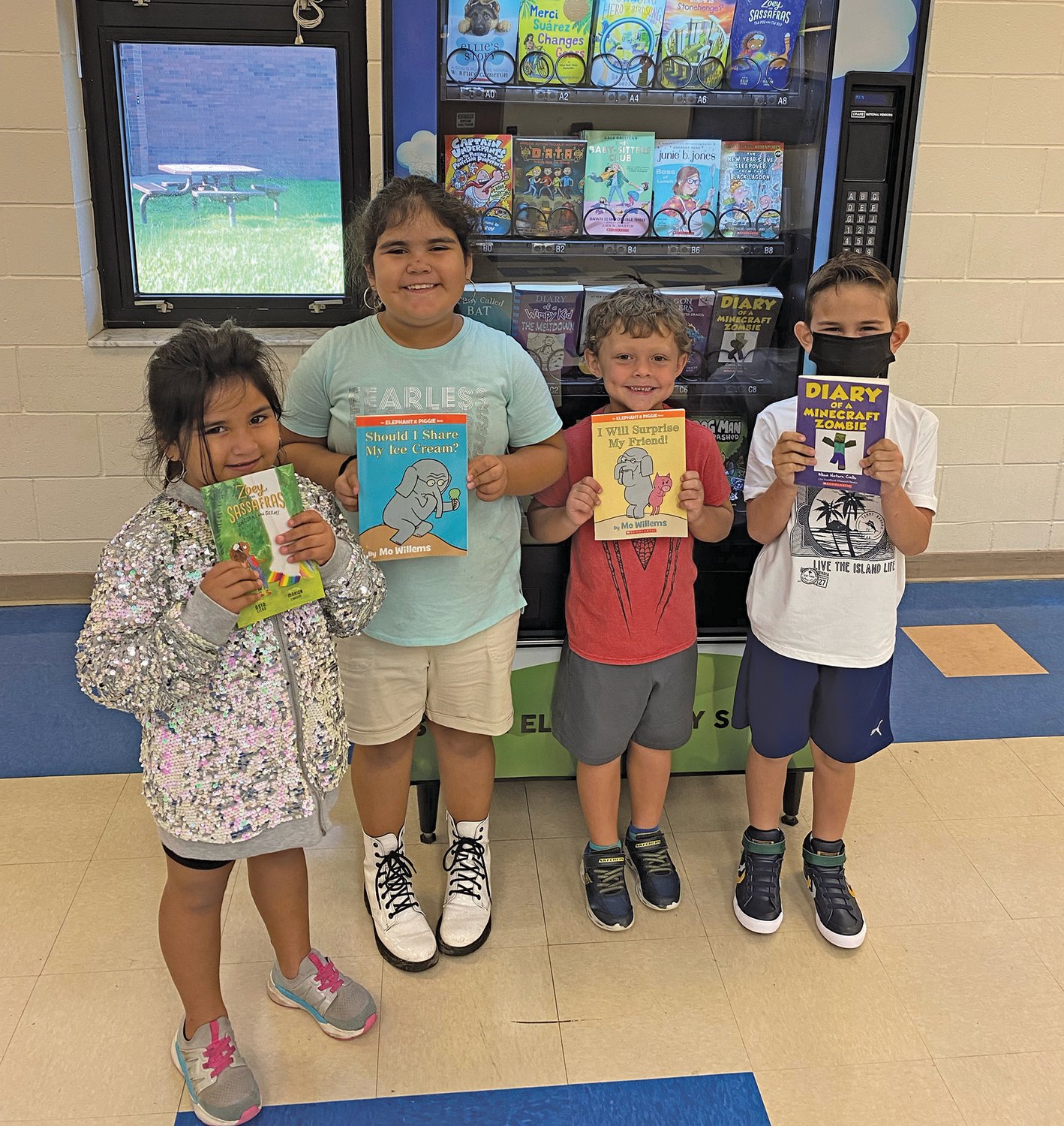 A few of the South Elementary students to reach their AR reading goal hold books they received as rewards from the book vending machine.